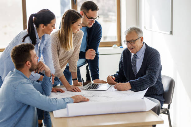 istock College professor examining blueprint with group of his students. 1274954332