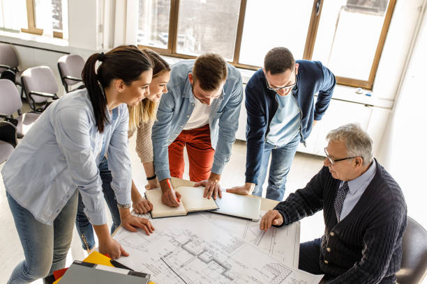 istock College architecture professor examining blueprint with group of his students. 1274954451