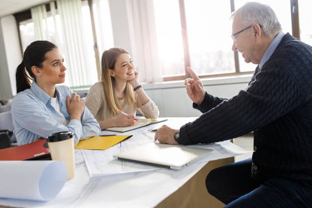 istock Two female college students listen to professor's lecture in class room. 1274956098