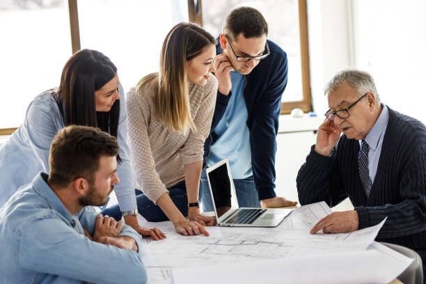 istock College professor examining blueprint with group of his students. 1274956691