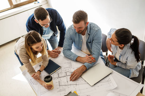 istock Group of architecture students examining blueprint . 1274958168
