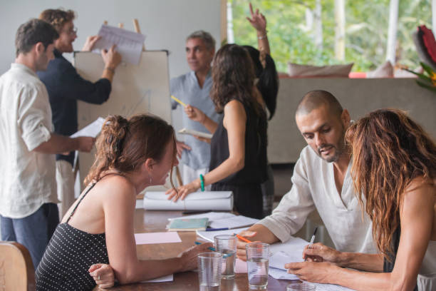 diverse group of multiethnic people having business meeting, seminar, presentation outdoor in tropical conference. team members listening attentively to a cheerful sharp speaker holding a presentation - attentively imagens e fotografias de stock