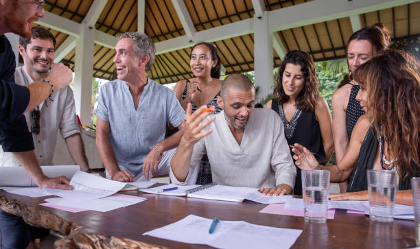 istock Happy diverse multiethnic business team members talking, discussing and brainstorming on project paperwork at meeting, seminar or presentation outdoor in tropical conference. 1274963487