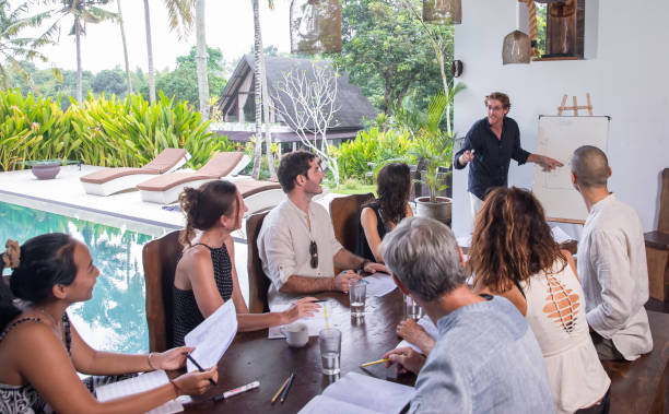 groupe diversifié de personnes multiethniques ayant réunion d’affaires, séminaire, présentation en plein air dans la conférence tropicale. les membres de l’équipe écoutent attentivement un haut-parleur vif joyeux tenant une présentation - tropical climate audio photos et images de collection