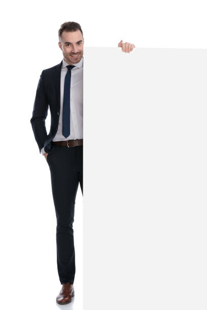 istock Smiling businessman presenting empty billboard and holding hand in pocket 1274974819