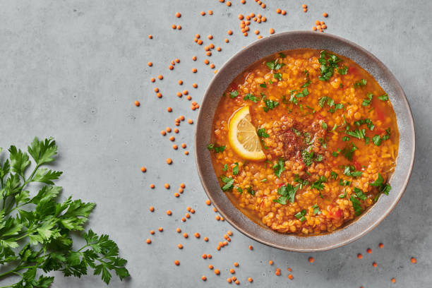 sopa de tomate de lentejas rojas con perejil y limón en plato gris sobre tablero de mesa de hormigón. plato vegetariano. copiar espacio - sopa de lentejas rojas fotografías e imágenes de stock