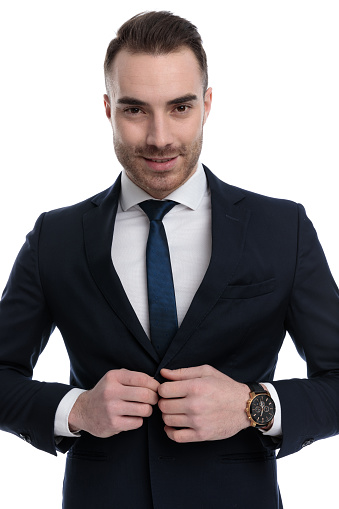 Positive businessman unbuttoning his jacket and smiling while standing on white studio background