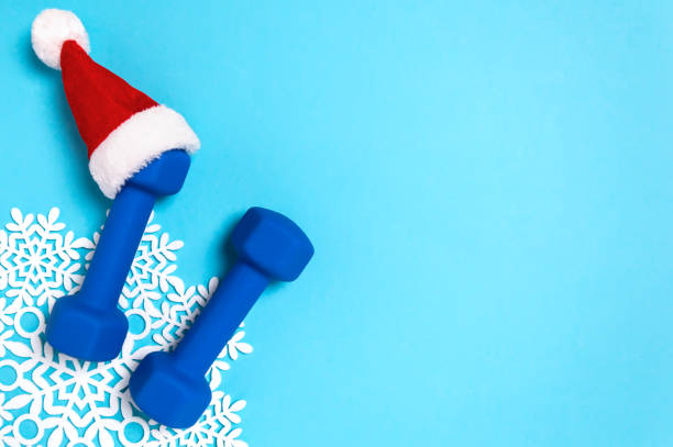 istock Christmas sport flat lay with dumbbells in red Santa's hat on blue background 1274995621