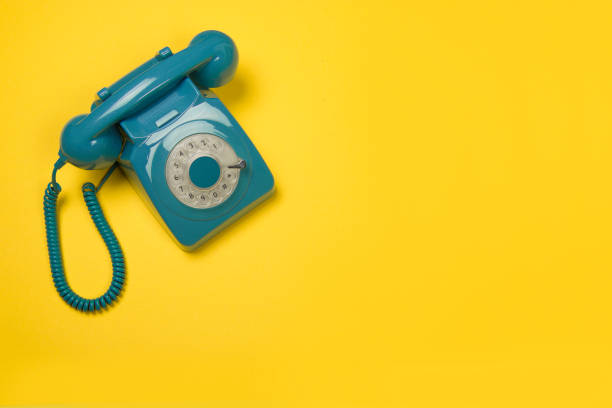 Blue retro telephone seen from a high angle on a yellow background