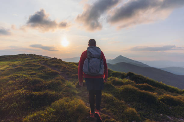 istock Man backpacker hiking at the scenic mountain valley during bright sunset 1275018106