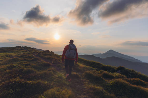 istock Man backpacker hiking at the scenic mountain valley during bright sunset 1275018830