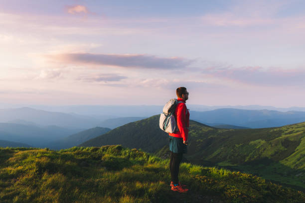 istock Man backpacker hiking at the scenic mountain valley during bright sunset 1275019691