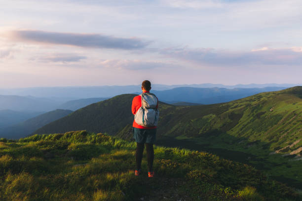 istock Man backpacker hiking at the scenic mountain valley during bright sunset 1275019931