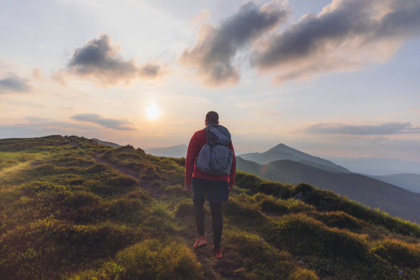 istock Man backpacker hiking at the scenic mountain valley during bright sunset 1275020214
