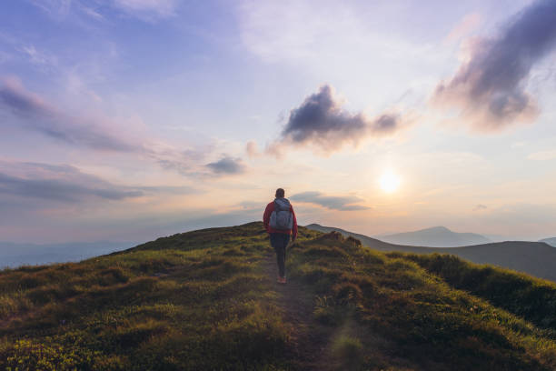 istock Man backpacker hiking at the scenic mountain valley during bright sunset 1275020385