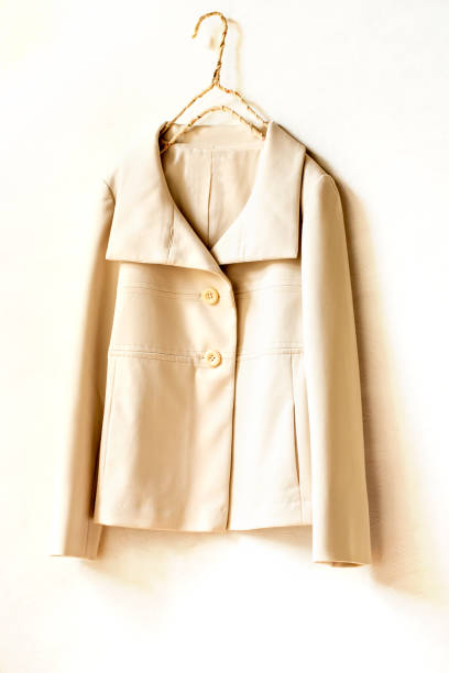 istock beige or white jacket hanging on clothes hanger on white background. 1275023114