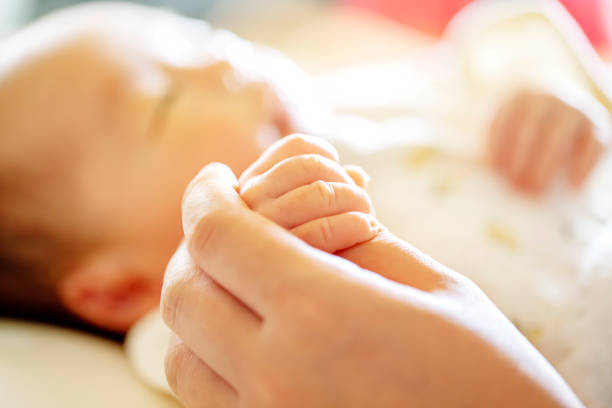 手を握る。生まれたばかりの赤ん坊を親の手に渡す - 誕生 ストックフォトと画像