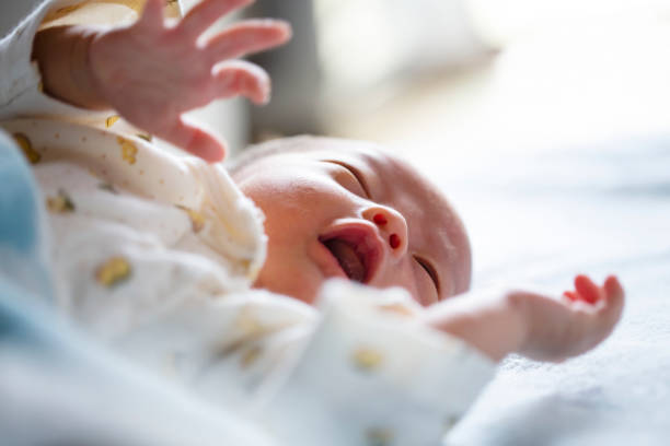 istock Cute newborn baby lying on bed, crying. Close up. 1275025634