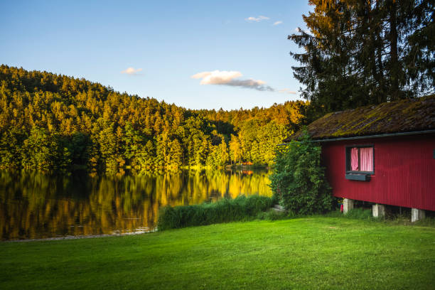 Old fisherman's wooden hut on an idyllic lake in the forest in the evening. Calm mood, clear sky, natural forest. Bavaria, Germany, Europe