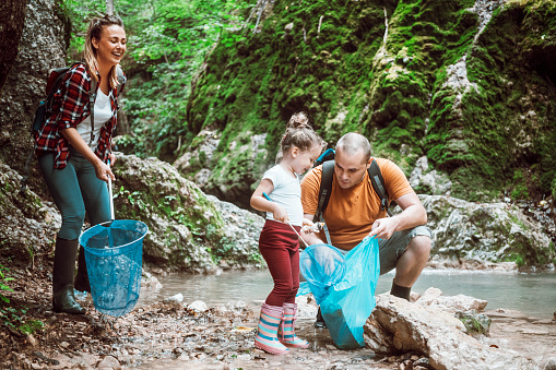 Young family cleaning small river from garbage