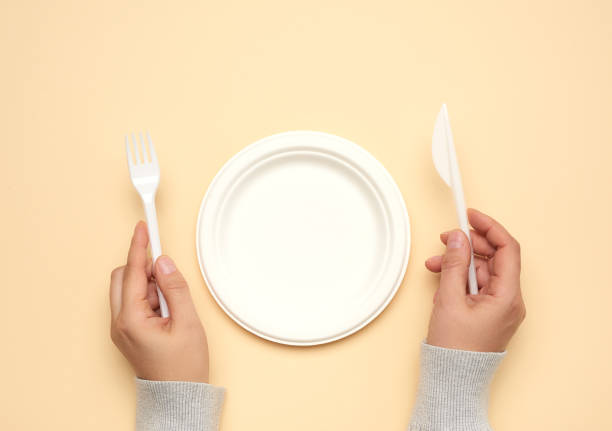 istock empty white paper plate and female hands are holding disposable fork and knife 1275050147
