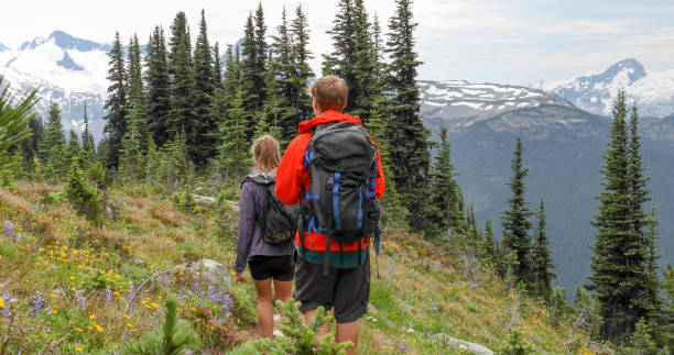 istock Hiking couple walk along forested trail through alpine meadow 1275062125