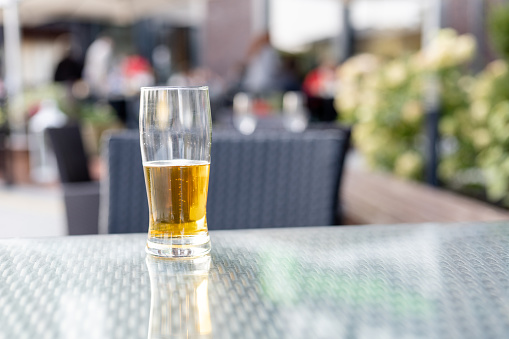a glass of beer on a table in a street restaurant