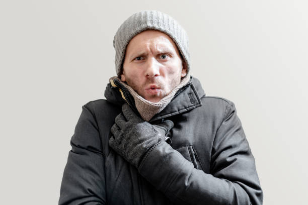 istock Young freezing man in winter clothes on gray background 1275071410