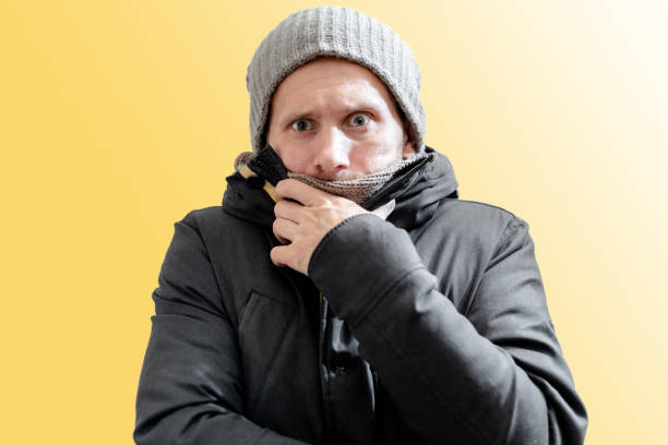 istock Young freezing man in winter clothes on yellow background 1275071415