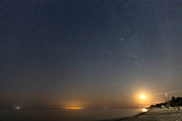 istock night starry sky with rising moon over sea beach 1275071433