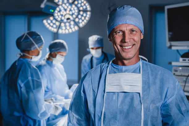 portret męskiego chirurga z zespołem lekarzy na tle w sali operacyjnej. - surgery emergency room hospital operating room zdjęcia i obrazy z banku zdjęć