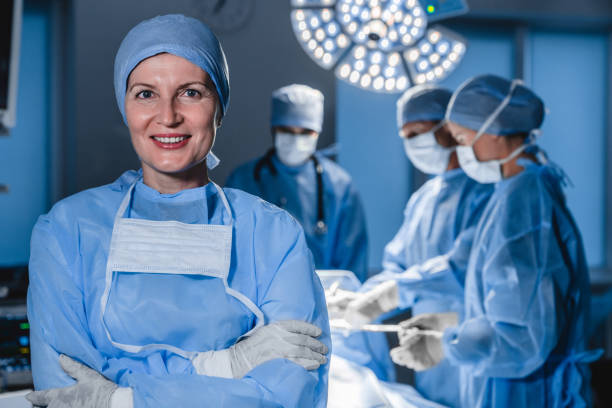 ritratto di medico caucasico con sfondo sfocato dell'equipe medica che fa un'operazione chirurgica in ospedale - surgeon isolated paramedic operating room foto e immagini stock