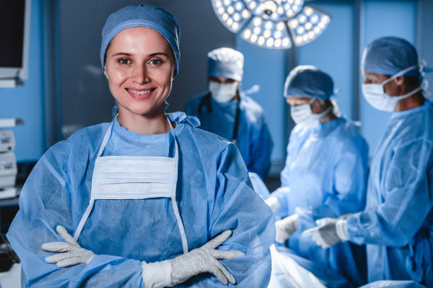 portret uśmiechniętej kobiety chirurga z operacją w tle. - surgeon isolated paramedic operating room zdjęcia i obrazy z banku zdjęć