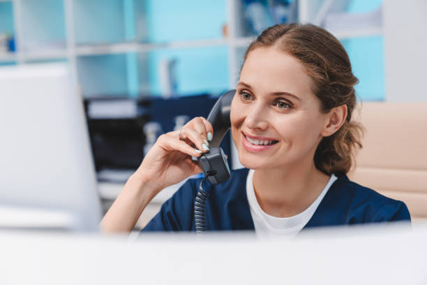 istock Young female doctor practitioner working at reception desk while answering phone calls and scheduling appointments 1275072701