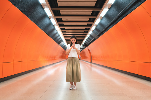 Mujer asiática enviando mensajes de texto en la estación de metro photo