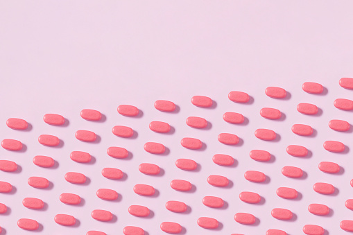 Pills in a row on soft pink background