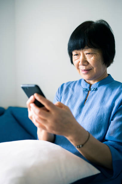 istock Senior woman sitting on sofa using smartphone 1275097529