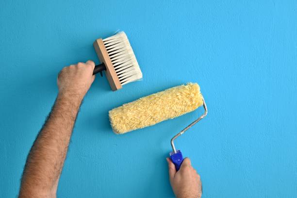 istock Painting with a brush and roller on a blue wall. 1275106726