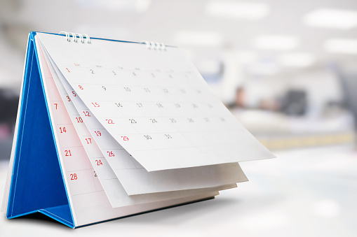 Calendar page flipping sheet on office table interior background business schedule planning appointment meeting concept