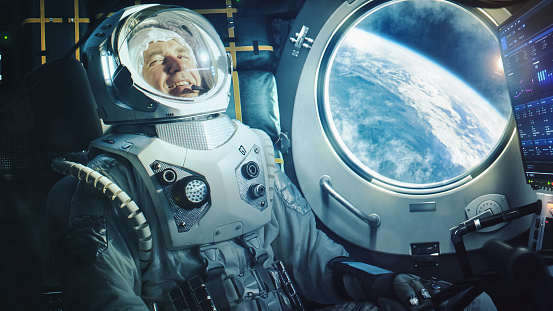 Portrait of a Happy Astronaut on a Space Ship In Orbit. Cosmonaut in a Futuristic Space Suit is Full of Joy and Having a Video Call. VFX Graphics Shot from the International Space Station.