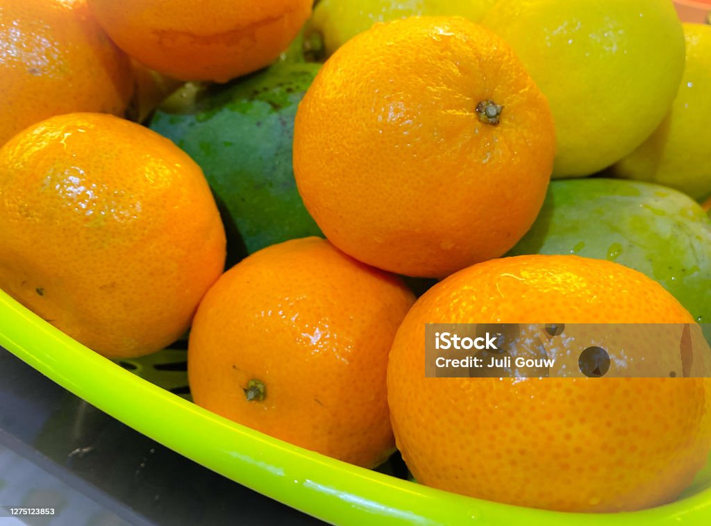 Fresh fruits Fresh oranges and other fruits are placed in the green basket Agriculture Stock Photo