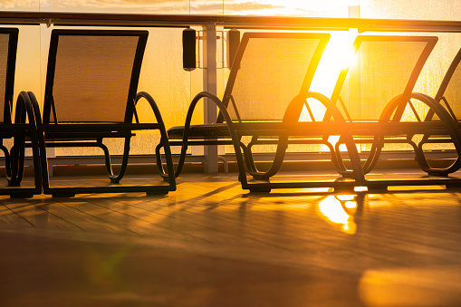 rows of empty sun bathing bench on board a cruise wooden deck sunset moment