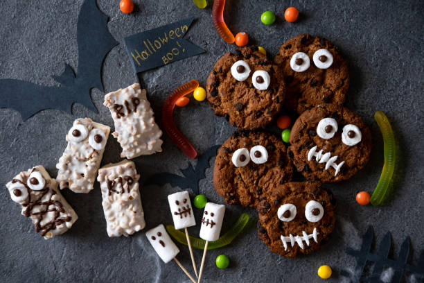 istock Modern Halloween background. Halloween candy bar: funny monsters made of biscuits with chocolate and ghosts marshmallow close-up on the table. Halloween party decoration. Trick or treat concept. 1275174991
