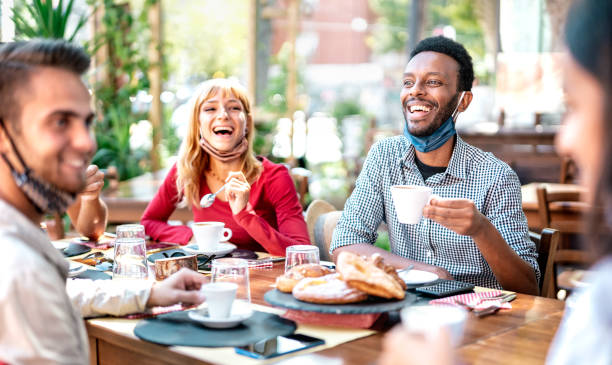 friends drinking cappuccino at coffee house - young people having fun together at restaurant - new normal lifestyle concept with happy guys and girls at cafe bar - bright vivid filter - breakfast eating people teens imagens e fotografias de stock