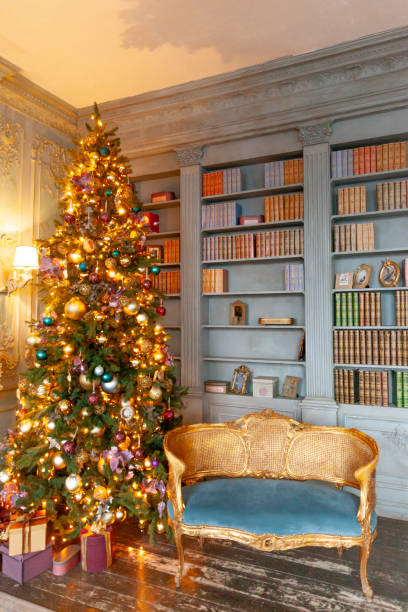 istock Classic Christmas New Year decorated interior room home library with fireplace. Christmas tree with gold ornament decorations. Modern classical style interior design apartment. Christmas eve at home 1275196933