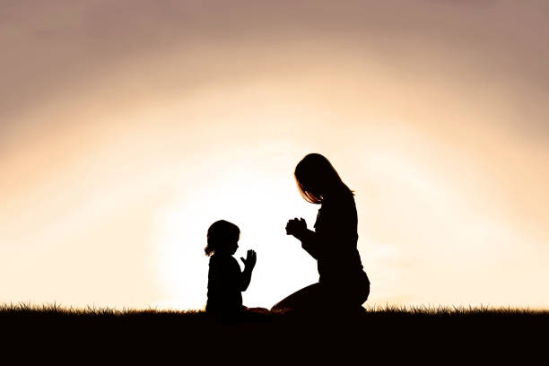 istock Mother Praying with her Young Child Outside at Sunset. 1275206462