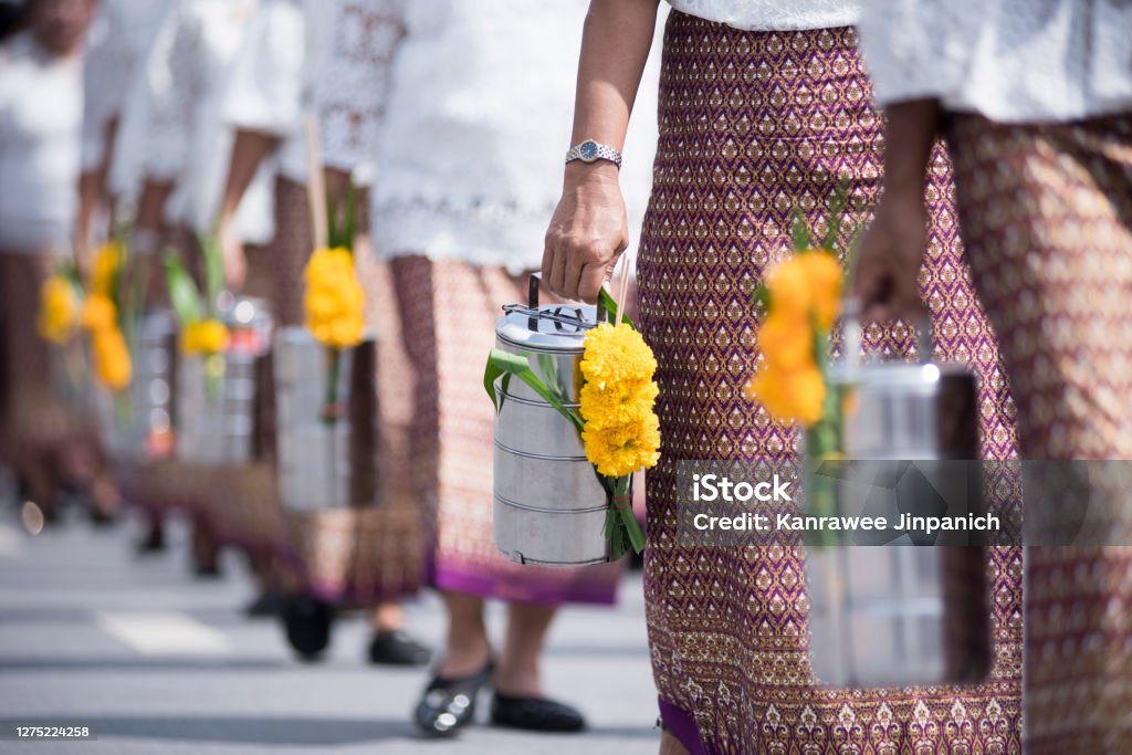 Thailand people walking to temple in Buddhist holy day for offering some food Pinto to monk. Tumbler or called Pinto in Thailand it use for contain fresh food to carry everywhere or make merit in Temple for offering some food to monk and pray,focus on hands of a old lady  Pinto. Spirituality Stock Photo