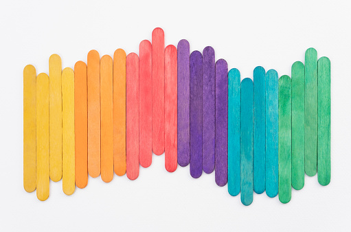 Colorful rainbow wooden popsicles on white paper background, abstract color sticks arrange for adding text letters design, kids back to school concept