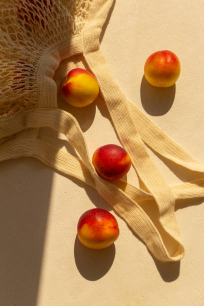 Fresh juicy nectarines in a cotton bag on a white background