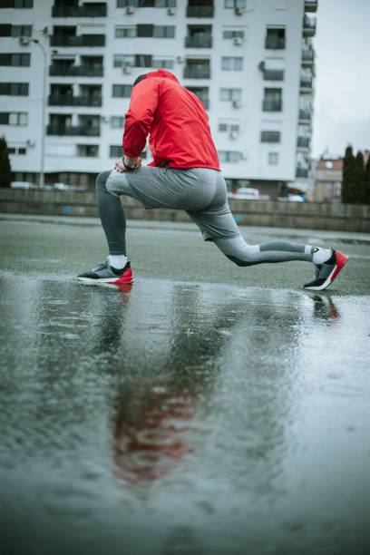 istock Man in red wind jacket is stretching on rainy day 1275246315